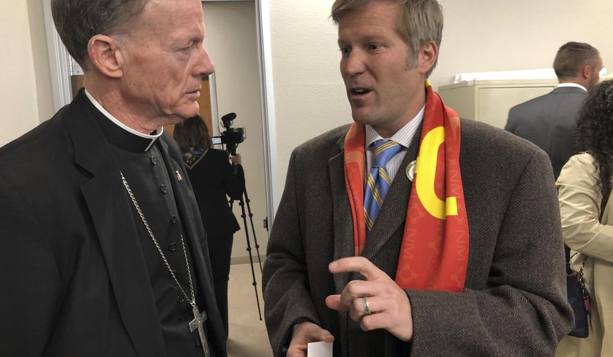 Santa Fe Archbishop John Wester, left, talks to Albuquerque Mayor Tim Keller, right, at Catholic Charities in Albuquerque, N.M., on Wednesday, March 13, 2019. Keller announced Wednesday that "hundreds" of migrants from Central America and Brazil are expected to arrive in the city in the coming weeks and volunteers are preparing for visitors. (AP Photo/Russell Contreras)