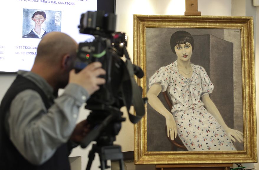 A cameraman films a painting, "Portrait of Kiki", falsely attributed to 20th century painter Moise Kisling, during a press conference announcing the conclusion of the preliminary phase of an investigation of 21 paintings seized by Carabinieri during an exhibition in 2017, in central Rome, Wednesday, March 13, 2019. (AP Photo/Alessandra Tarantino)