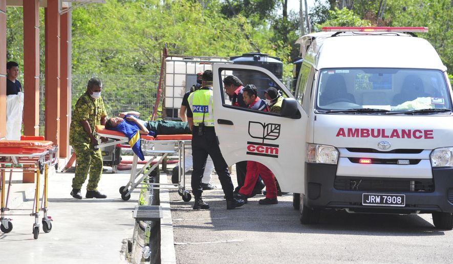 Emergency personnel unload a student from an ambulance after toxic chemical spill in Pasir Gudang, Johor state, on Wednesday, March 13, 2019. Malaysia's education ministry has ordered 34 schools to be closed in southern Johor state after toxic waste believed dumped in a river sickened dozens of students and teachers. (AP Photo/Thomas Yong)