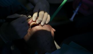 FILE- In this April 3, 2018, file photo, a dentist works on polishing and contouring the teeth of a patient at his dental office in Virginia Beach. Va. Roughly 1 in 4 Americans don’t have dental coverage, according to industry figures. Employers are by far the biggest provider of dental coverage in the U.S., accounting for nearly half of all enrollees, followed by the government’s Medicaid plan for low-income people. (Kristen Zeis/The Virginian-Pilot via AP, File)