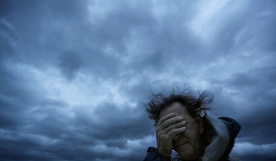 FILE - In this Friday, Sept. 14, 2018 file photo, Russ Lewis covers his eyes from a gust of wind and a blast of sand as Hurricane Florence approaches Myrtle Beach, S.C. According to a scientific report from the United Nations released on Wednesday, March 13, 2019, climate change, a global major extinction of animals and plants, a human population soaring toward 10 billion, degraded land, polluted air, and plastics, pesticides and hormone-changing chemicals in the water are making the planet an increasing unhealthy place for people. (AP Photo/David Goldman)