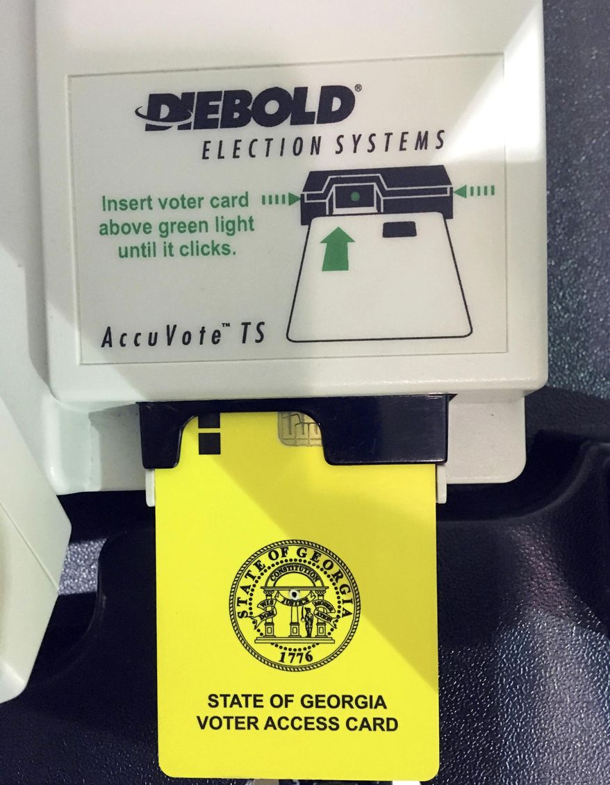 FILE- This May 22, 2018 file photo, shows a voter access card inserted in a voting reader during voting in the Georgia primary in Kennesaw, Ga. Just months after a highly contentious race for Georgia governor, the state Senate has approved a House plan to purchase new electronic touchscreen voting machines that print a paper ballot statewide. It's a big step toward replacing Georgia's current outdated voting system, which offers no auditable paper trail. But some say it's a big step in the wrong direction. (AP Photo/Mike Stewart, File)