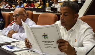FILE - In this July 21, 2018 photo, a member of the National Assembly studies the proposed constitutional update in Havana, Cuba. Some observers see the new constitution as a merely cosmetic update aimed at assuring one of the world’s last communist systems won’t get another revamp until long after the passing of its founding fathers, while others see the potential for a slow-moving but deep set of changes that will speed the modernization of Cuba’s economically stagnant authoritarian bureaucracy. (Abel Padron, Agencia Cubana de Noticias via AP, File)