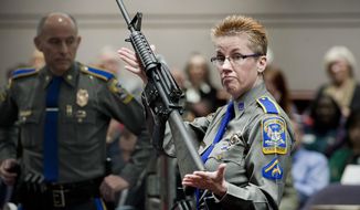 FILE - In this Jan. 28, 2013, file photo, firearms training unit Detective Barbara J. Mattson, of the Connecticut State Police, holds a Bushmaster AR-15 rifle, the same make and model used by Adam Lanza in the 2012 Sandy Hook School shooting, during a hearing at the Legislative Office Building in Hartford, Conn. The Connecticut Supreme Court is expected to rule Thursday, March 14, 2019, whether or not Remington Arms, which manufactured the rifle, can be sued for making the rifle that was used in the massacre. (AP Photo/Jessica Hill, File)