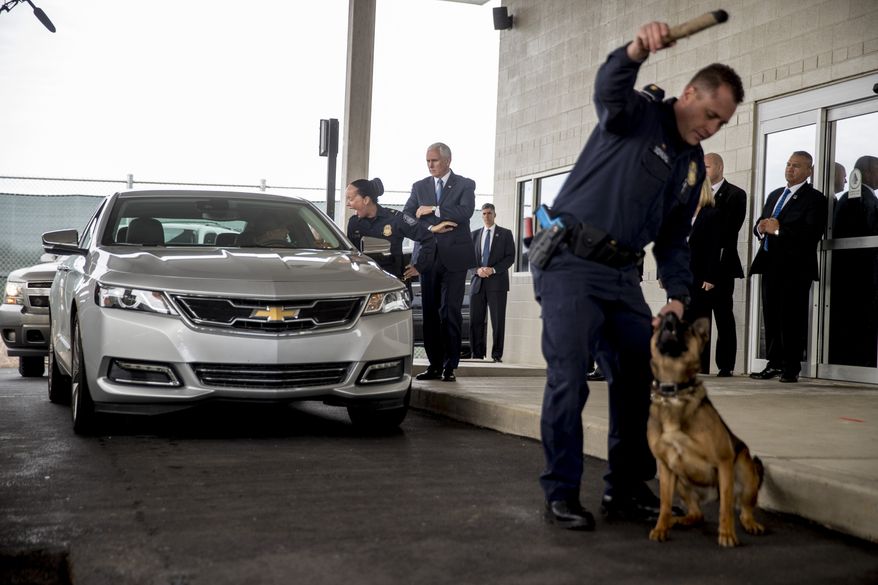 Customs agent Patrick Dowling rewards his dog Balbina after he finds a bag of drugs in a vehicle as Vice President Mike Pence, center, observes Point of Entry training at the U.S. Customs and Border Protection Advanced Training Facility in Harpers Ferry, W.Va., Wednesday, March 13, 2019. (AP Photo/Andrew Harnik)