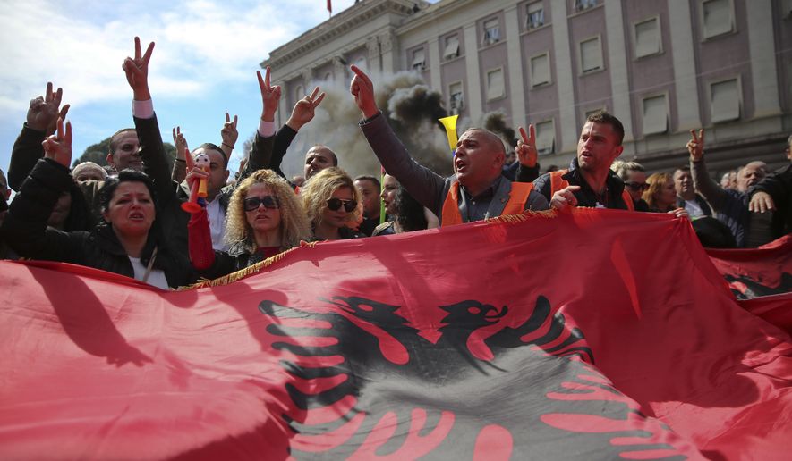 Protesters waving an Albanian flag shout slogans near the government building during a protest in Tirana, Albania on Saturday, March 16, 2019. Albanian opposition supporters clashed with police while trying to storm the parliament building Saturday in a protest against the government which they accuse of being corrupt and linked to organized crime.(AP Photo/Visar Kryeziu)