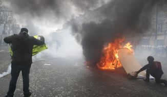 Yellow vests protesters set a burricade afire on the Champs Elysees avenue Saturday, March 16, 2019 in Paris. French yellow vest protesters clashed Saturday with riot police near the Arc de Triomphe as they kicked off their 18th straight weekend of demonstrations against President Emmanuel Macron. (AP Photo/Christophe Ena)