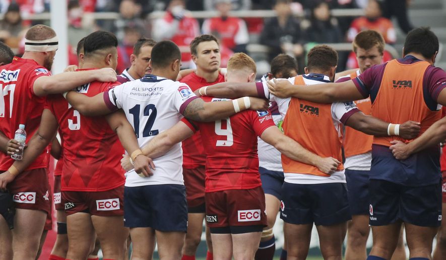 Players offer a silent prayer for victims of a mass shooting at New Zealand before their Super Rugby match between Sunwolves and Reds in Tokyo, Saturday, March 16, 2019. (AP Photo/Koji Sasahara)