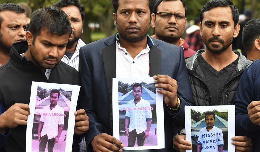 Friends of a missing man Zakaria Bhuiyan hold up photos of him outside a refuge center in Christchurch, Sunday, March 17, 2019. The live-streamed attack by an immigrant-hating white nationalist killed dozens of people as they gathered for weekly prayers in Christchurch.  (Mick Tsikas/AAP Image via AP)