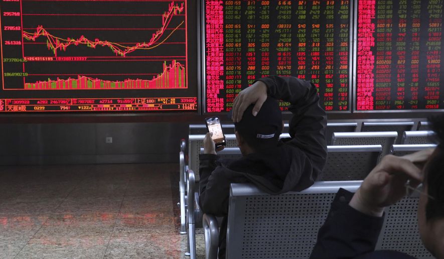 An investor plays a mobile chess game while watching stock prices at a brokerage in Beijing, China, Tuesday, March 19, 2019. Asian shares were mixed in muted trading Tuesday as investors awaited the U.S. Federal Reserve meeting later in the week. (AP Photo/Ng Han Guan)