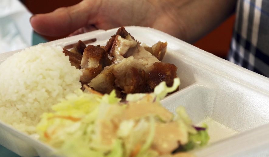 In this Thursday, March 14, 2019 photo, Belinda Lau, manager of the Wiki Wiki Drive Inn takeout restaurant in Honolulu, holds a polystyrene foam box containing an order of roast pork, rice and salad. Hawaii would be the first state in the nation to ban most plastics used at restaurants, including polystyrene foam containers, if legislation lawmakers are considering is enacted. The aim is to cut down on waste that pollutes the ocean. (AP Photo/Audrey McAvoy)
