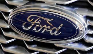 FILE- This Feb. 15, 2018, file photo shows a Ford logo on the grill of a car on display at the Pittsburgh Auto Show. Ford Motor Co. is repackaging a previously announced manufacturing investment in the Detroit area and now says it will spend $900 million and create 900 new jobs over the next four years. Most of the new workers will build a new generation of electric vehicle at Ford’s existing factory in Flat Rock, Michigan, south of Detroit, which will see an $850 million investment.   (AP Photo/Gene J. Puskar, File)