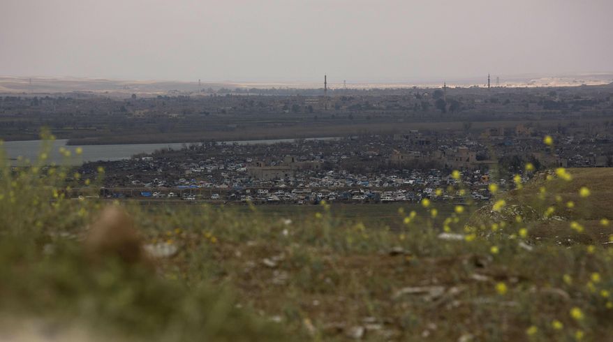 In this Sunday, March 17, 2019, photo, the Islamic State group's last pocket of territory in Baghouz, Syria, as seen from a distance. On Tuesday, a spokesman for U.S.-backed forces fighting IS in Syria says his fighters are in control of an encampment in the village of Baghouz where IS militants have been besieged for months. (AP Photo/Maya Alleruzzo)