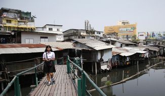 In this March 19, 2019, photo, Thai student walks over a footbridge bridge through dilapidated homes along the Phra Khanong canal in Bangkok, Thailand. Ahead of next weekend&#39;s general election, the widespread dissatisfaction among the country&#39;s poor with how the economy is doing may be balanced out by strong support for the junta from big business and wealthier Thais. For many voters, the still bigger issue is the role of the military after it took over in a 2014 coup. (AP Photo/Sakchai Lalit)