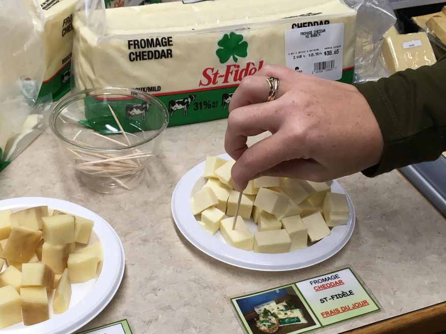 In this Sept. 19, 2018 photo, a tourist tries a sample of cheese from the Fromagerie Saint-Fidele in Saint-Fidele, Quebec in Canada. Fromagerie Saint-Fidele makes cheeses with terroir accents, offering fresh cheddar and Swiss to customers each day. (AP Photo/John Marshall)