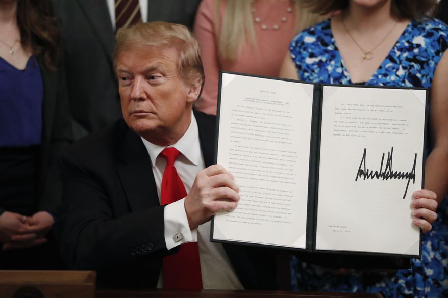 President Donald Trump holds up an executive order requiring colleges to certify that their policies support free speech as a condition of receiving federal research grants, after signing, Thursday March 21, 2019, in the East Room of the White House in Washington. (AP Photo/Jacquelyn Martin)