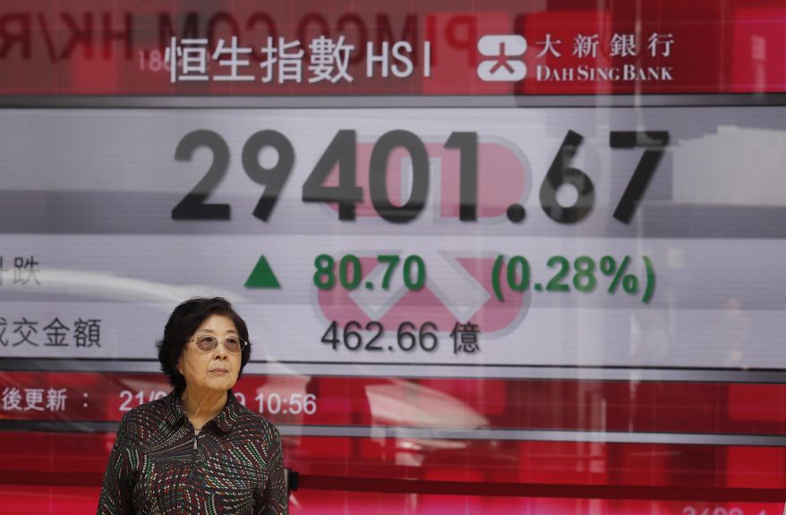 A woman stands in front of an electronic board showing Hong Kong share index outside a bank in Hong Kong, Thursday, March 21, 2019. Shares in Asia are mostly higher after the Federal Reserve said it has ruled out interest rate increases for this year. (AP Photo/Kin Cheung)