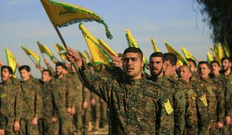 In this Feb. 13, 2016 file photo, Hezbollah fighters hold flags as they attend the memorial of their slain leader Sheik Abbas al-Mousawi, who was killed by an Israeli airstrike in 1992, in Tefahta village, south Lebanon.  (AP Photo/Mohammed Zaatari, File) **FILE**