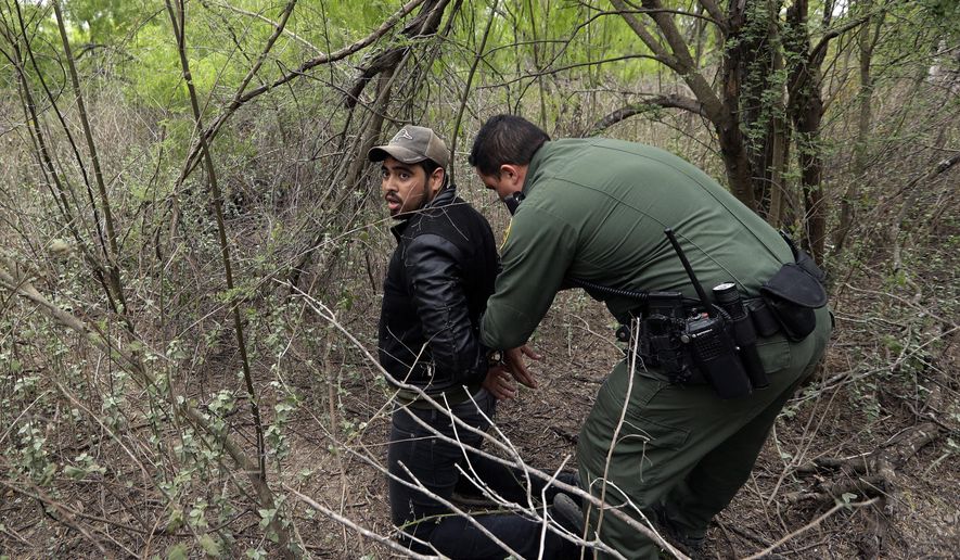 In this Thursday, March 14, 2019, photo, a Border Patrol agent apprehends a person suspected of having entered the U.S. illegally near McAllen, Texas. While many adults crossing the border on their own in South Texas try to flee agents, most migrant parents and children wait to surrender so they can be processed and released into the United States. (AP Photo/Eric Gay)