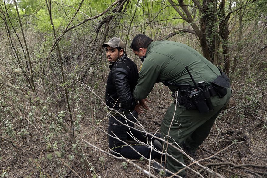 In this Thursday, March 14, 2019, photo, a Border Patrol agent apprehends a person suspected of having entered the U.S. illegally near McAllen, Texas. While many adults crossing the border on their own in South Texas try to flee agents, most migrant parents and children wait to surrender so they can be processed and released into the United States. (AP Photo/Eric Gay)