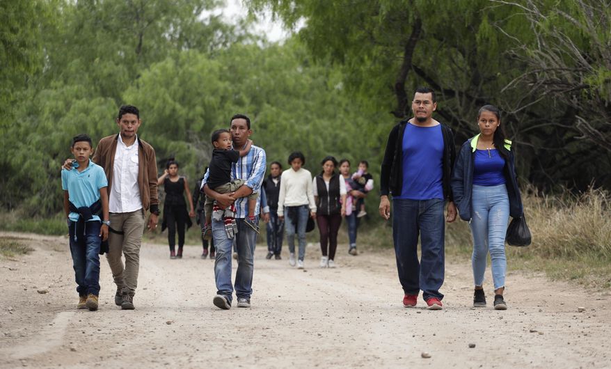 In this Thursday, March 14, 2019, photo, a group of migrant families walk from the Rio Grande, the river separating the U.S. and Mexico in Texas, near McAllen, Texas. The migrants said they crossed the river in an inflatable raft and were hoping to be apprehended by the Border Patrol so they could be processed and released. (AP Photo/Eric Gay)