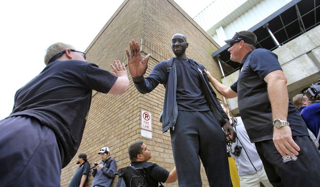 In this Wednesday, March 20, 2019 photo, Colt Kohler, 11, gets a high-five from Central Florida center Tacko Fall, as dad Erik Kohler looks on as UCF departs for the NCAA college basketball tournament in Orlando, Fla. Fall, at 7-foot-6 the tallest player in the game, at last gets to appear on the game&#x27;s biggest stage when UCF opens the NCAA Tournament on the college basketball&#x27;s biggest stage. (Joe Burbank/Orlando Sentinel via AP)