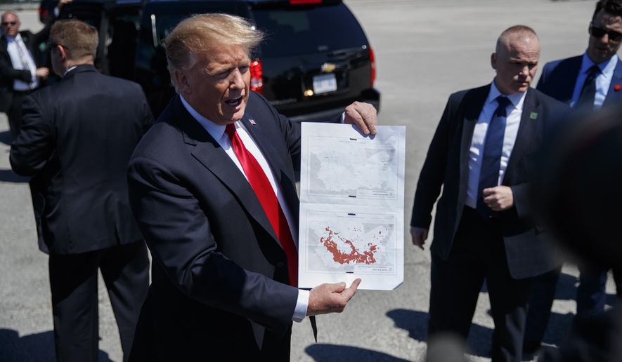 President Donald Trump holds a a copy of two maps of Syria as he arrives on Air Force One, Friday, March 22, 2019, at Palm Beach International Airport, in West Palm Beach, Fla. One map is awash in red shows IS controlled territory in Syria in November 2016. The other, without red, indicates that IS as of today no longer controls territory in Syria. (AP Photo/Carolyn Kaster)