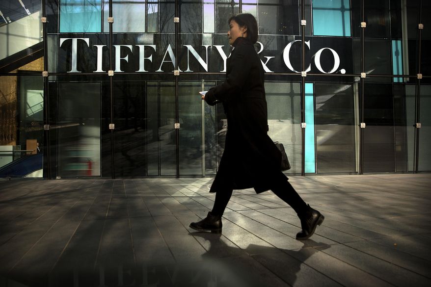 FILE- In this Nov. 29, 2018, file photo, a woman walks past a Tiffany & Co. store at a shopping mall in Beijing. Tiffany & Co. reports financial results on Friday, March 22, 2019. (AP Photo/Mark Schiefelbein, File)