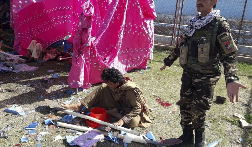 Afghan security force soldier stands over a wounded man following multiple explosions in Lashkar Gah city of Helmand province, southern Afghanistan, Saturday, Mar. 23, 2019. An Afghan official says that at least three have been killed in twin bomb explosions occurred during the Farmer’s Day ceremony in southern Helmand province. (AP Photo/Abdul Khaliq)