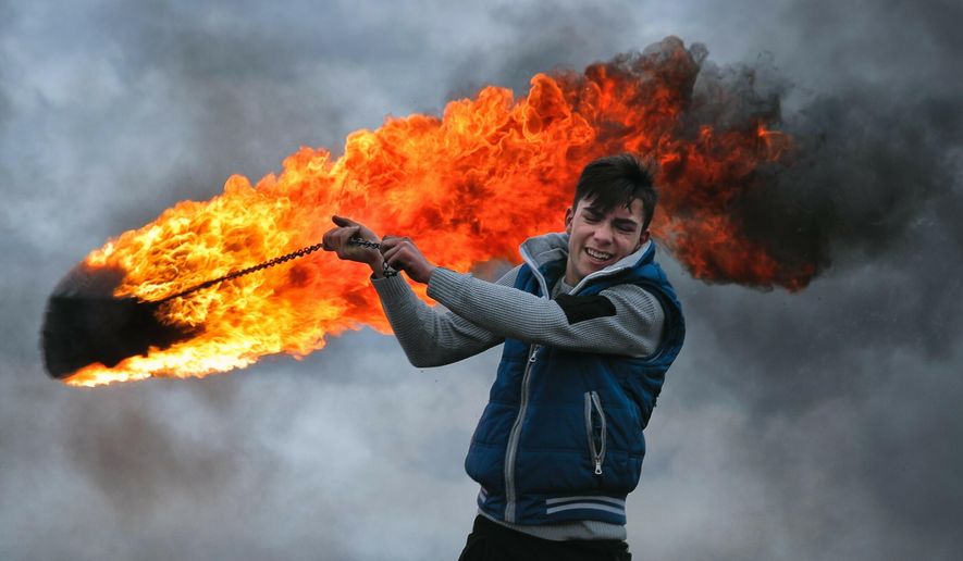 In this photo taken on Sunday, March 10, 2019, a young man spins a burning tire on a metal chain, during a ritual marking the upcoming Clean Monday, the beginning of the Great Lent, 40 days ahead of Orthodox Easter, on the hills surrounding the village of Poplaca, in central Romania&#x27;s Transylvania region. Romanian villagers burn piles of used tires then spin them in the Transylvanian hills in a ritual they believe will ward off evil spirits as they begin a period of 40 days of abstention, when Orthodox Christians cut out meat, fish, eggs, and dairy. (AP Photo/Vadim Ghirda)
