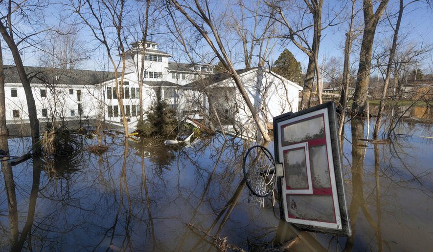 A wayward basketball hoop is seen behind a flooded home Friday, March 22, 2019, in Bellevue, Neb. Flooding in Nebraska has caused an estimated $1.4 billion in damage. The state received Trump's federal disaster assistance approval on Thursday. (Kent Sievers/The World-Herald via AP)/Omaha World-Herald via AP)