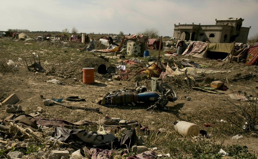 An Islamic State militant flag, foreground ,lies in a tent encampment after U.S.-backed Syrian Democratic Forces (SDF) fighters took control of Baghouz, Syriaon Saturday, March 23, 2019. The elimination of the last Islamic State stronghold in Baghouz brings to a close a grueling final battle that stretched across several weeks and saw thousands of people flee the territory and surrender in desperation, and hundreds killed. (AP Photo/Maya Alleruzzo)