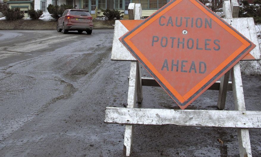 In this Thursday, March 21, 2019 photo, a sign warns drivers about potholes in Montpelier, Vt. It's muddier and bumpier this year than most since many parts of the northern New England states had especially rainy and snowy winters. (AP Photo/Lisa Rathke)