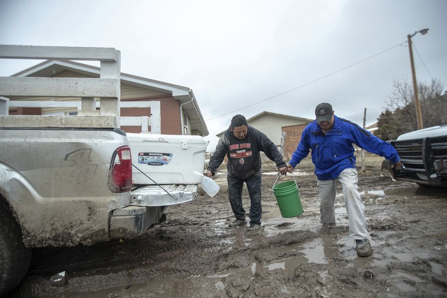 In this Monday, March 25, 2019 photo, tribal employees bring water, to elders and others who were stranded in their homes on the Pine Ridge Indian Reservation near Porcupine, S.D., following spring flooding. (Ryan Hermens/Rapid City Journal via AP)