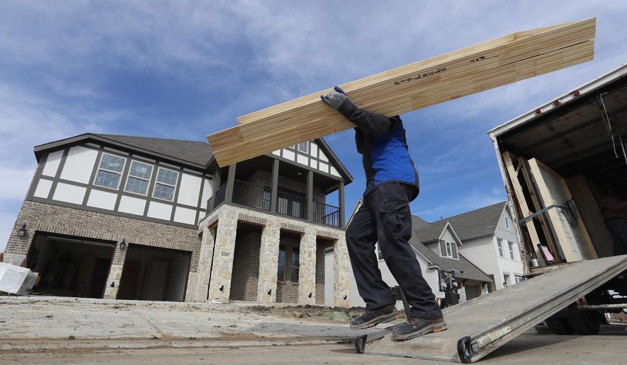 FILE- In this Feb. 20, 2019, file photo a worker carries interior doors to install in a just completed new home in north Dallas. On Tuesday, March 26, the Commerce Department reports on U.S. home construction in February. (AP Photo/LM Otero, File)