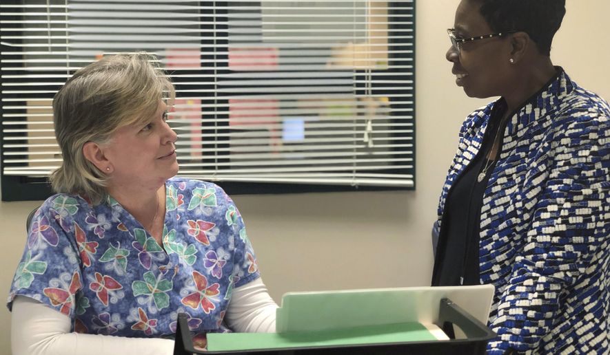 In this Feb. 28, 2019 photo, Linda Espinosa, left, a school nurse at Freedom Middle School in the Atlanta metro-area, speaks to school counselor, Tijuana Williams, about schoolgirls coming in to her office to get sanitary pads, in Atlanta. Georgia’s legislature is joining a nationwide effort to provide menstrual products for public school students in need. (AP Photo/Sanya Mansoor)