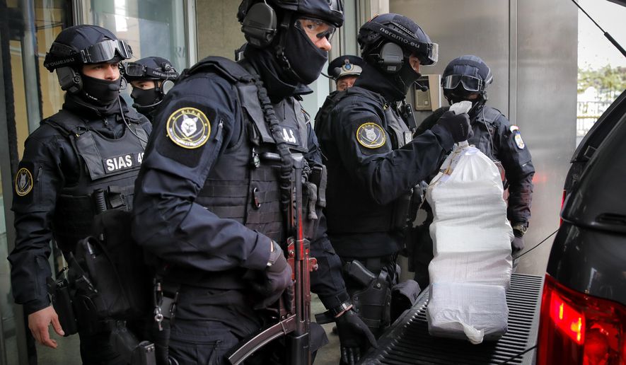 Romanian special police troops carry bags of cocaine outside the building of the Directorate for Investigating Organized Crime and Terrorism in Bucharest, Romania, Tuesday, March 26, 2019. Authorities captured over a tone of high purity cocaine with an estimated value of 300 million euros (338 million USD) from a capsized boat in the Danube Delta. (AP Photo/Vadim Ghirda)