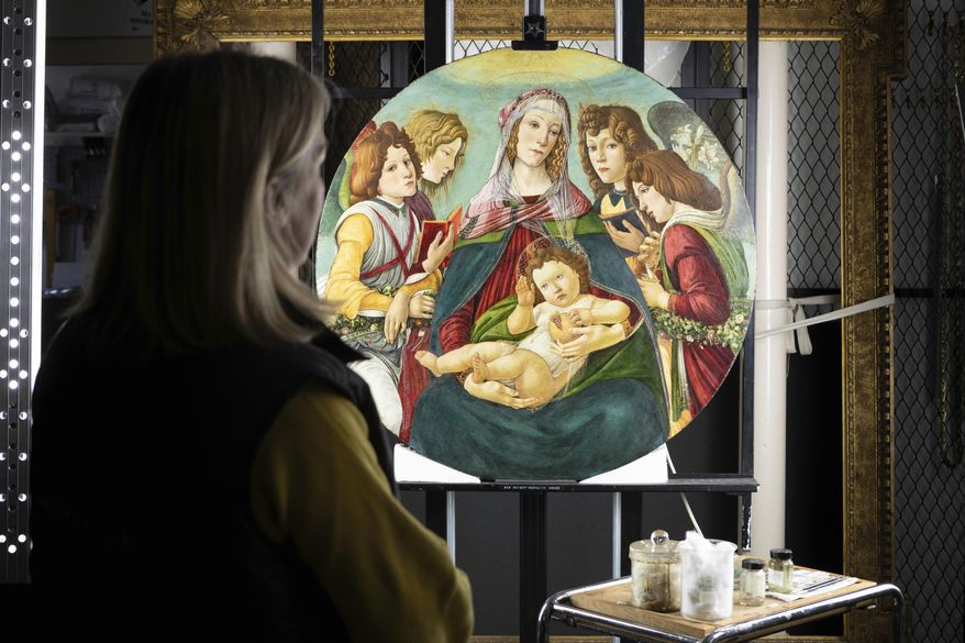 In this photo made available by English Heritage on Thursday March 28, 2019, English Heritage Conservator Rachel Turnbull completes the conservation of "Madonna of the Pomegranate", a painting revealed as a rare example by the workshop of Botticelli. After stripping back a century of yellowing varnish and surface dirt, the painting thought to be a fake Sandro Botticelli, in fact came from the master’s own Florence workshop. (Christopher Ison/English Heritage via AP)