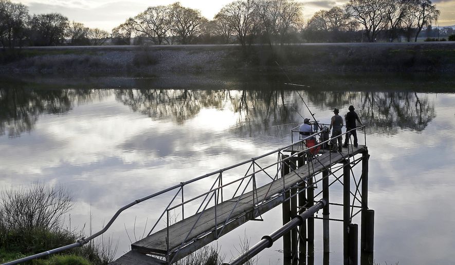 FILE - In this Feb. 23, 2016 file photo, people try to catch fish along the Sacramento River in the San Joaquin-Sacramento River Delta, near Courtland, Calif. The federal government has sued California over water policies it says violate state environmental protections. The lawsuit filed Thursday, March 28, 2019, in federal court in Sacramento challenges a plan that went into effect in December to increase water flows in the San Joaquin River. (AP Photo/Rich Pedroncelli, File)