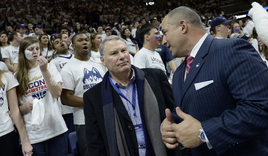 FILE - In this Feb. 13, 2017, file photo, American Athletic Conference commissioner Mike Aresco, center, talks with Connecticut athletic director David Benedict, right, before an NCAA college basketball game between UConn and South Carolina, in Storrs, Conn.Aresco says the league's new media rights deal with ESPN gives the AAC a platform similar to having its own branded network. The American and ESPN announced a 12-year agreement that runs through the 2031-32 school year. (AP Photo/Jessica Hill, File)