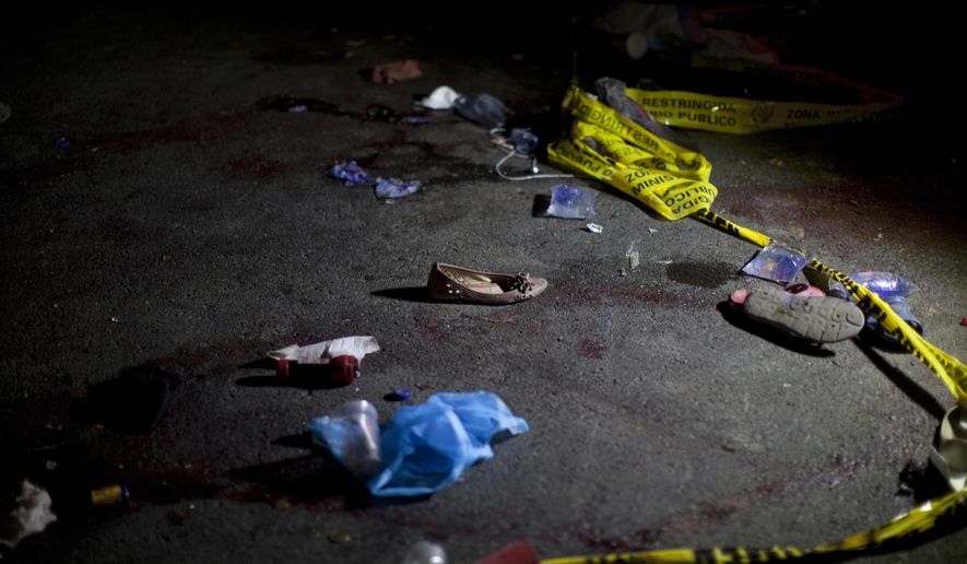 Yellow police tape and shoes lay on the ground in the place where an accident occurred, in Nahuala, Guatemala, early Thursday, March 28, 2019. A large truck slammed into a crowd gathered on a dark highway in western Guatemala, killing over a dozen people and leaving bodies scattered on the roadway, firefighters said. (AP Photo/Sandra Sebastian)