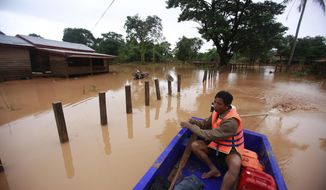 FILE - In this July 26, 2018, file photo, a man paddles his boat through a flooded village after a dam in southeastern Laos collapsed,  in the Sanamxay district, Attapeu province, Laos. A United Nations human rights expert is urging Laos to focus less on big, foreign-invested dam and railway contracts and devote more resources to helping its children and the poor.  Philip Alston, the U.N. rapporteur on poverty, said Laos’ economy can only thrive if its leaders do a better job of educating and caring for all of its people.(AP Photo/Hau Dinh, File)