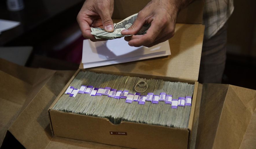 In this June 27, 2017, file photo, the proprietor of a medical marijuana dispensary prepares his monthly tax payment, more than $40,000 in cash, at his Los Angeles store. (AP Photo/Jae C. Hong, File)