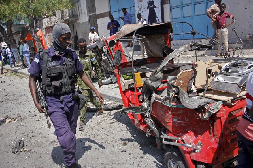A policeman walks past a destroyed vehicle after an attack using an explosives-laden vehicle on a restaurant in Mogadishu, Somalia Thursday, March 28, 2019. Police say at least 10 people have been killed and others wounded in the car bomb blast outside the restaurant in the Somali capital. (AP Photo/Farah Abdi Warsameh) ** FILE **