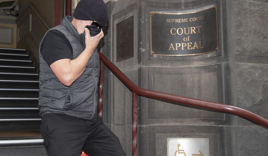 Workplace bullying claimant David Hingst covers his face as he leaves the Court of Appeal in Melbourne, Australia Friday, March 29, 2019. The Australian appeals court on Friday dismissed a bullying case brought by the engineer Hingst who accused his former supervisor of repeatedly breaking wind toward him. (Ellen Smith/AAP Image via AP)