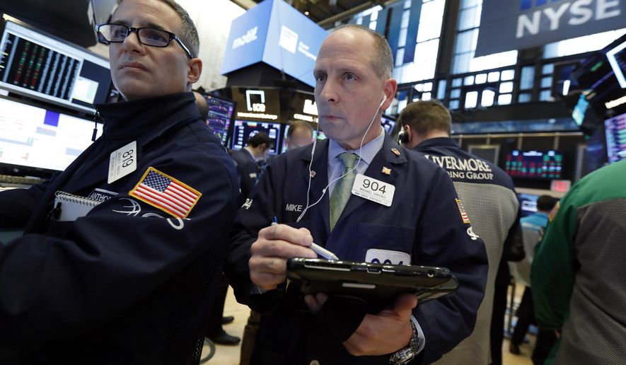 FILE- In this March 7, 2019, file photo specialist Anthony Rinaldi, left, and trader Michael Urkonis work on the floor of the New York Stock Exchange. The U.S. stock market opens at 9:30 a.m. EDT on Friday, March 29. (AP Photo/Richard Drew, File)