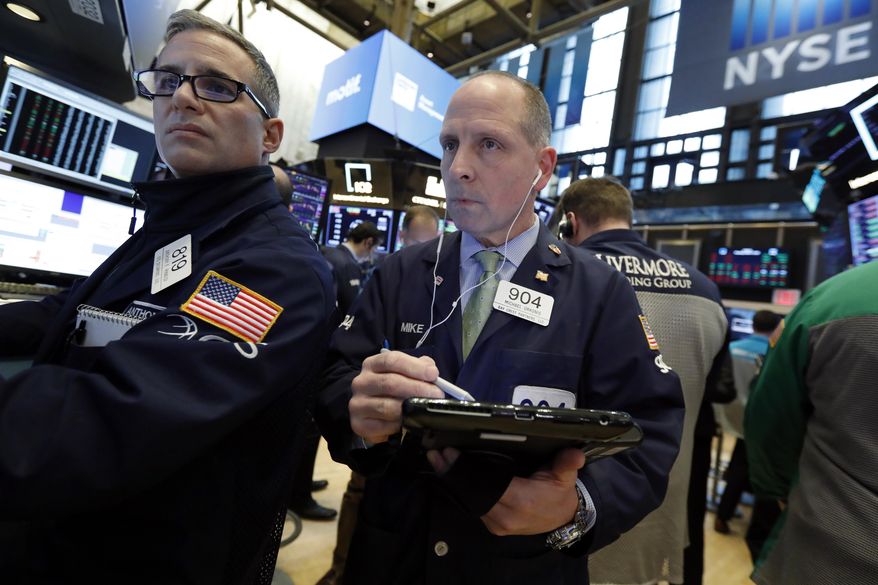 FILE- In this March 7, 2019, file photo specialist Anthony Rinaldi, left, and trader Michael Urkonis work on the floor of the New York Stock Exchange. The U.S. stock market opens at 9:30 a.m. EDT on Friday, March 29. (AP Photo/Richard Drew, File)