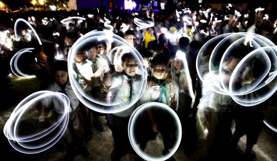 Philippine Boy Scouts play with their flashlights at the countdown for the 12th Earth Hour event Saturday, March 30, 2019 in suburban Makati city east of Manila, Philippines. Earth Hour is the symbolic switching off of the lights for one hour to help minimize fossil fuel consumption as well as mitigate the effects of climate change. (AP Photo/Bullit Marquez)