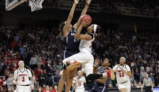 Connecticut forward Napheesa Collier (24) defends against Louisville guard Asia Durr (25) who goes up for two points during the second half of a regional championship final in the NCAA women&#x27;s college basketball tournament, Sunday, March 31, 2019, in Albany, N.Y. Louisville forward Sam Fuehring (3), guard Arica Carter (11) and forward Bionca Dunham (33) watch from the floor. (AP Photo/Kathy Willens)