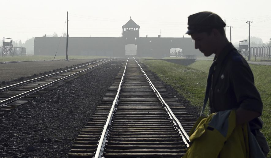 FILE - In this file photo dated Friday, July 29, 2016, a man crosses the iconic rails leading to the former Nazi death camp of Auschwitz-Birkenau in Poland. Police official Malgorzata Jurecka in Poland said Sunday March 31, 2019, an American visitor to the former Auschwitz-Birkenau death camp attempted to steal a metal part of the rail tracks where prisoners were unloaded, and he has been charged with attempted theft. (AP Photo/Alik Keplicz, FILE)